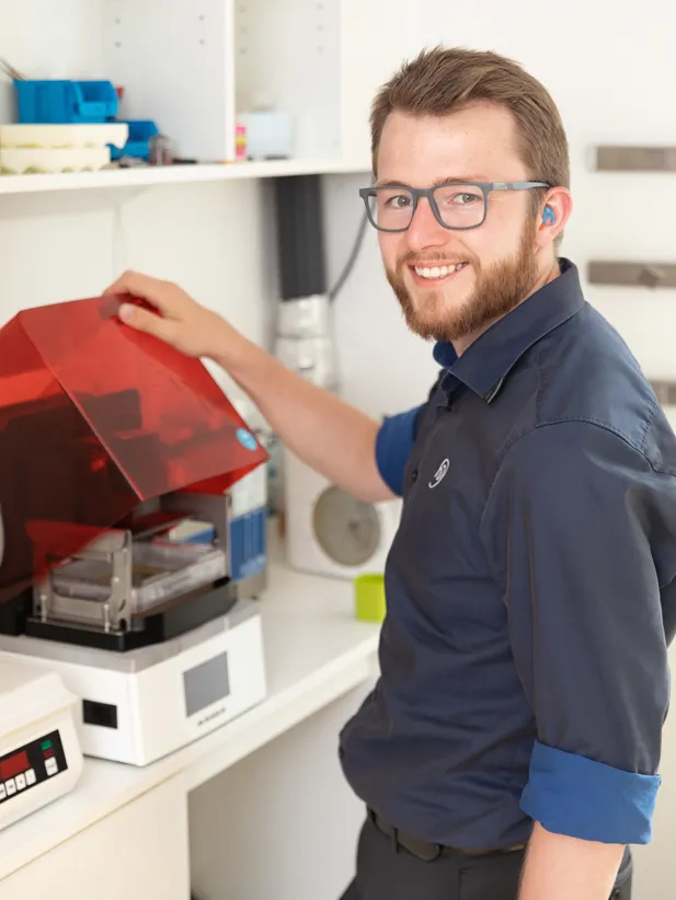 Jonas Marufke steht an einem 3D Drucker.